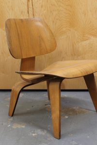 photo of side angle of light wood 1950s Eames LCW chair
