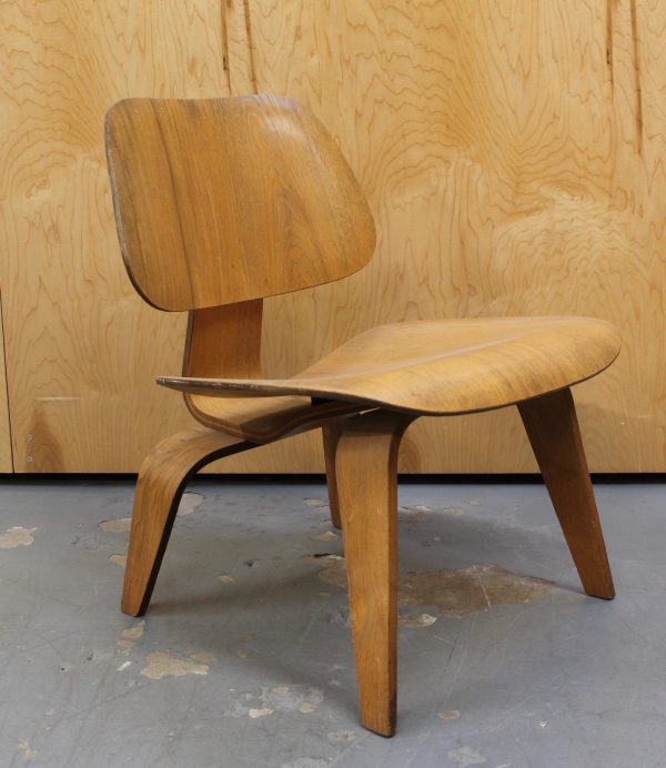photo of side angle of light wood 1950s Eames LCW chair