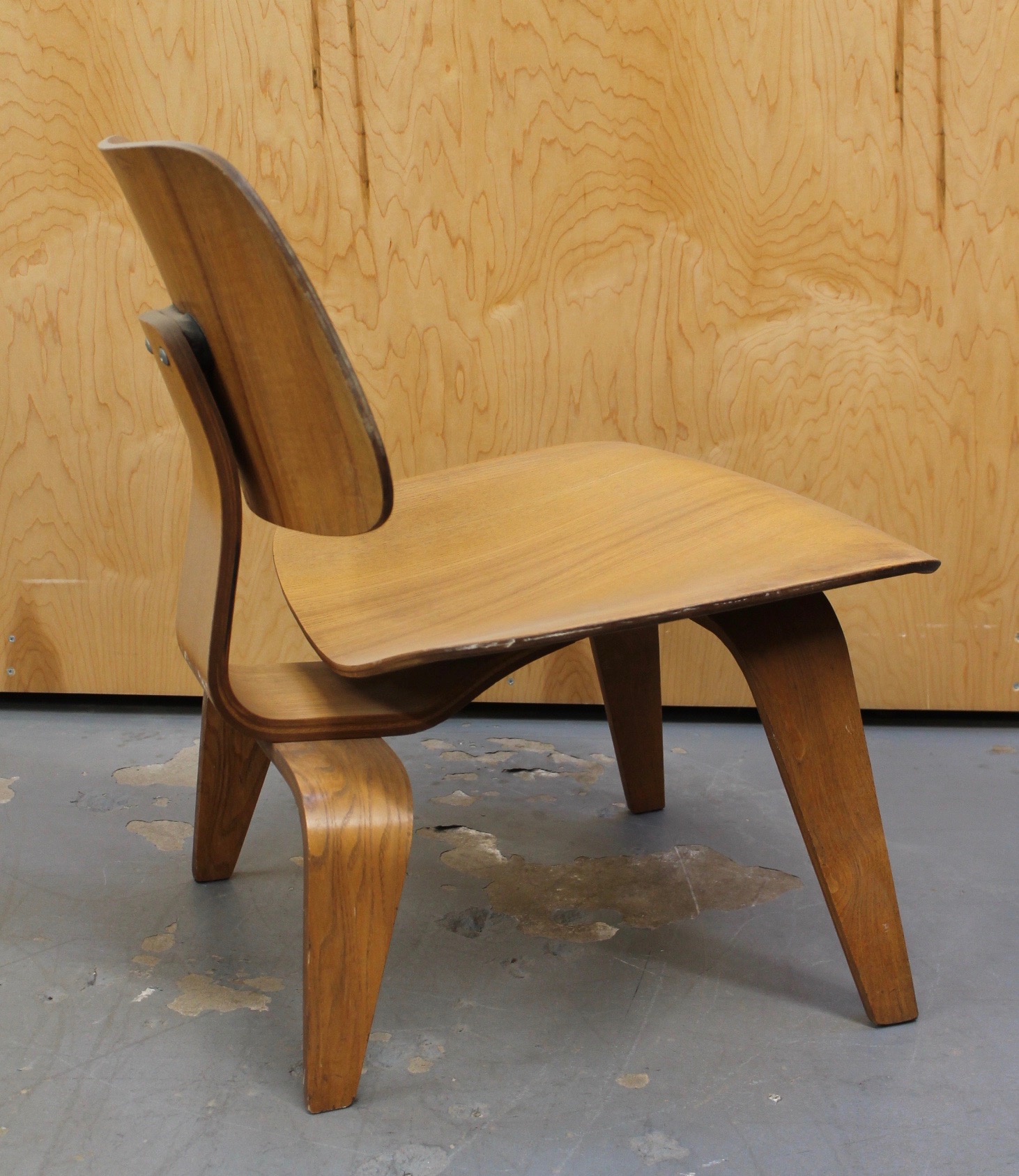 photo of side of light wood 1950s Eames LCW chair